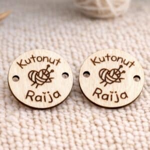 pyöreä vaaleasta koivuvanerista tehty käsityömerkki johon kaiverrettu teksti "Kutonut Raija" keskelle kaiverrettu sydämen muotoinen lankakerä