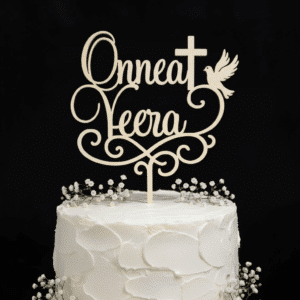 Kakkukoriste rippijuhlaan jossa lukee "Onnea Veera". Tekstin lisäksi kakkukoristeeessa on köynnöksiä, risti ja kyysky. Kakkukoriste on asetettuna kakkuun, jossa harsokukkia. Tausta on tumma.