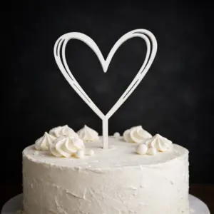 Puinen sydämen muotoinen kakkukoriste vaalean kakun päällä juhlakäytössä